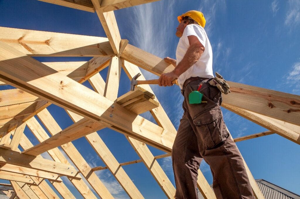 Dachdecker, der an der Dachkonstruktion eines im Bau befindlichen Gebäudes arbeitet