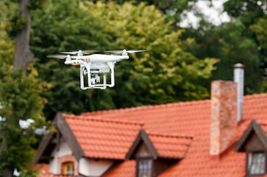Moderner RC-Quadcopter. RC-Drohne mit Kamera, die über das Dach des Hauses fliegt. Selektiver Fokus